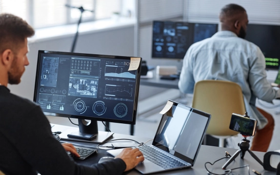 IT professionals monitoring network security on multiple screens in an office.